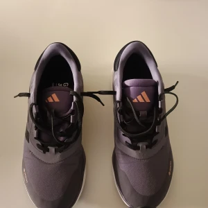 Adidas Gore-Tex sneakers - Snygga Adidas sneakers med Gore-Tex material i en stilren lila färg. Skorna har svarta detaljer och en vit sula med bra dämpning. Perfekta för utomhusaktiviteter med sin vattentäta design och snörning för optimal passform.