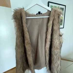 Beige pälsväst från Esmara - Säljer en snygg beige pälsväst från Esmara i storlek S. Perfekt för höst och vinter, den är både stilren och varm. Västen har en mjuk insida och är öppen framtill, vilket gör den lätt att matcha med olika outfits. Ett måste för garderoben! Har klippt västen kortare! 