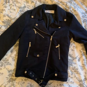 Svart jacka från Ivyrevel - Snygg svart jacka från Ivyrevel med coola dragkedjedetaljer och knappar. Perfekt för höst och vår, den har en modern bikerstil med långärmade ärmar och en tight passform. Jackan är i nyskick och redo för nya äventyr!