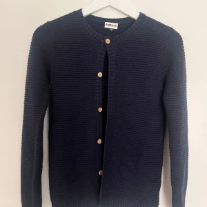 Kofta - Grov stickad tröja, mörk blå, bruna knappar. Har endast användts ett fåtal gånger. Jag har vanligtvis S, men den satt lite tajt så skulle passa XS.