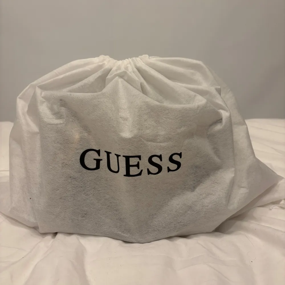 Säljer nu min skitsnygg handväska i beige färg från Guess. Jag har använt den kanske 3-4ggr så den är i nyckick. Den har guldfärgade detaljer och en avtagbar axelrem med Guess-logga. Väskan har flera fack och en dragkedja framtill. Perfekt för både vardag. Laukut & Käsilaukut.