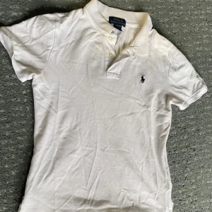 Vit Ralph Lauren pikè - En vit Ralph lauren piké som är använd ett par fåtal gånger men är nästan som en ny. Den är helt vit och har inga fläckar. Ny pris ligger på runt 1000 kronor. Storlek är 150/76 och är från 10-12 år.