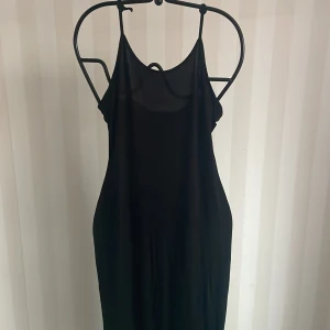 Svart klänning från Nelly  - Snygg svart klänning från Nelly med smala axelband. Perfekt för en kväll ute eller en fest. Den har en enkel och elegant design som gör den lätt att matcha med olika accessoarer. Klänningen är i ett mjukt och bekvämt material.