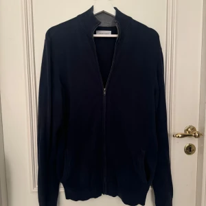 Blå tröja med dragkedja från pier one - Säljer en stilren blå tröja från pier one med dragkedja framtill. Perfekt för höst och vår, med långärmad design som håller dig varm. Passar både till vardags och festliga tillfällen. Tröjan är använd och lite urtvättad