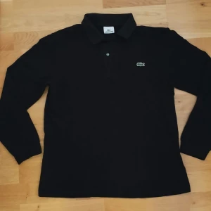 Lacoste långärmad piké - Svart långärmad Lacoste piké. Sparsamt använd. Storlek: 4.