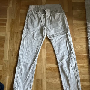 Beige Levi's jeans - Säljer ett par beige Levi's jeans, modell 551. De har en klassisk design med fem fickor och knappgylf. Perfekta för en avslappnad stil.