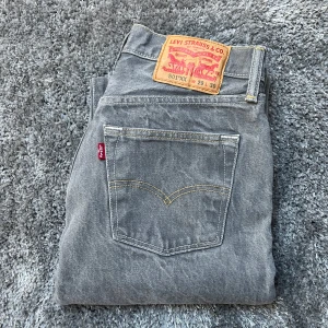 Grå Levis 501 Jeans - Säljer ett par klassiska grå Levis 501 jeans. De har en rak passform, knappgylf och är relativt i kort i längden (när precis ner till marken på mig som är 162 cm lång), 