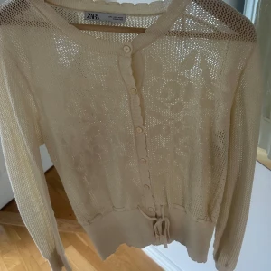 Beige kofta från Zara - Säljer en beige kofta från Zara med knappar framtill och knytband i midjan. 