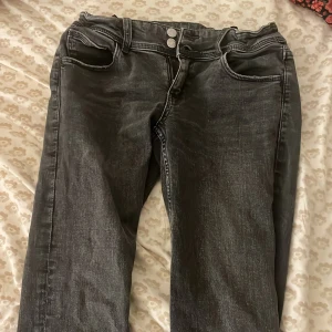 Svarta jeans med knappar - Snygga svarta jeans med knappar fram och bakfickor med lock. Perfekta för en avslappnad stil. De har en klassisk design med en bootcut passform