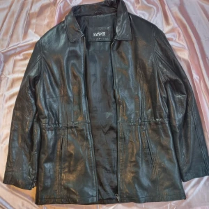 Svart skinnjacka från Kasper - Snygg svart skinnjacka från Kasper i storlek L. Jackan har en klassisk krage och dragkedja framtill. Perfekt för en stilren look.