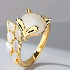 Guldfärgad ring med rävdesign - Unik guldfärgad ring med en charmig rävdesign. Ringen har en vit pärlemorskimrande sten som utgör rävens huvud och svans, vilket ger en elegant och lekfull look. Perfekt för att lägga till en touch av personlighet till din stil.