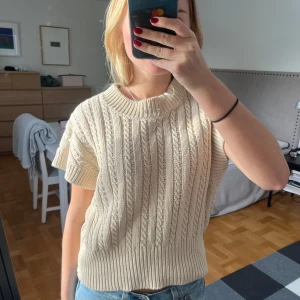 Beige stickad topp - Säljer en snygg beige stickad topp från Lindex. Den har korta ärmar och ett ribbat mönster.