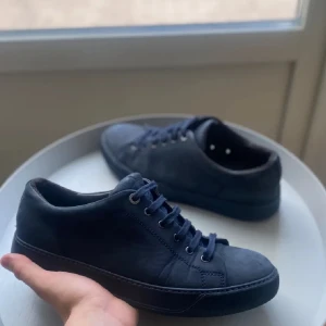 Mörka blåa sneakers från Lanvin (kan bytas) - Snygga svarta sneakers från Lanvin med klassisk snörning. Perfekta för en stilren look. Skorna har en robust sula och en diskret design som passar till många olika outfits. Lagningslappar i hälen men inget som syns från utsidan eller känns. Är lite smutsiga på bilden med enkelt att tvätta