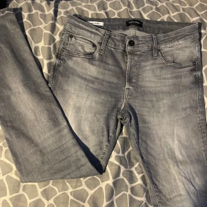 Grå jeans från Jack & Jones - Snygga grå jeans från Jack & Jones i modellen Slim Glenn. De har en slim passform med klassisk femficksdesign och knappar. Perfekta för en stilren look. Skick: 8/10. | W32 L32 