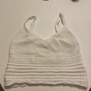 Vit stickad linnetopp - Säljer en söt vit stickad linnetopp med smala axelband. Toppen har en v-ringad design och är perfekt för varma dagar. Den är både stilren och bekväm.