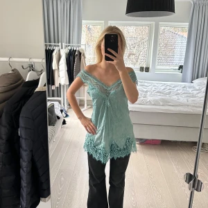 Mintgrön spetslinne - Säljer ett mintgrönt linne med vacker spetsdetalj längs kanterna. Linnet har en lös passform och är ärmlöst med en djup v-ringning. Man kan ha den på flera olika sätt, off shoulder eller vanligt. Så skönt material. Ingen storlek men uppskattar till S