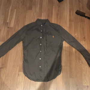 Ralph Lauren skjorta - Säljer en stilren olivgrön skjorta från Ralph Lauren. Skjortan är Slim fit och storlek S. Så skulle säga att den passar folk runt 175 och uppåt. Jag på bild är 183 cm. Pris är it hugget i sten!