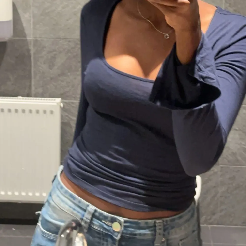 Snygg mörkblå topp med långa ärmar och djup urringning. Perfekt för en stilren look. Passar bra till jeans eller kjol.. Yläosat.