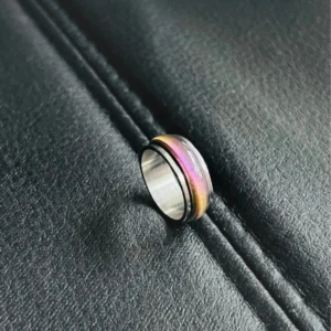 Prismatic Spin - Aurora Glass Ring - US storlek 7, diameter 17,3 mm, omkrets 54,4 mm. En unik ring i rostfritt stål med ett roterbart regnbågsfärgat glasband som skiftar i rosa, lila och andra nyanser beroende på ljus och vinkel. Perfekt som en stilfull stressring.