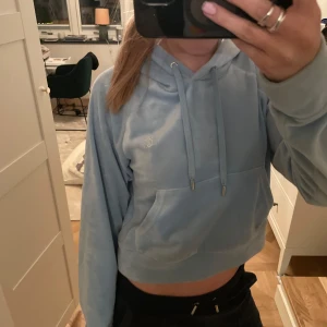 Ljusblå juicy hoodie  - Säljer en ljusblå hoodie från Juicy med en glittrig text på ryggen. Tröjan har en bekväm passform med långa ärmar och en praktisk magficka. Perfekt för en avslappnad stil.