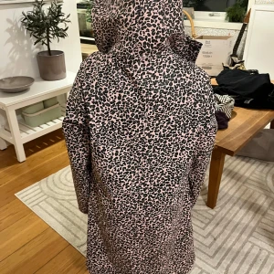 Leopardmönstrad regnjacka med luva - Snygg leopardmönstrad regnjacka i rosa och svart med huva. Perfekt för regniga dagar med stil. Jackan har en rak passform och är utrustad med dragkedja framtill.