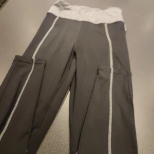 Svarta träningsleggings med grå midja i S - Snygga svarta träningsleggings med en bekväm grå midja. De har kontrasterande sömmar som ger en sportig look. Perfekta för gymmet eller yoga.