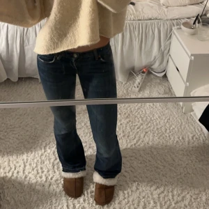 Blå bootcut jeans - Snygga blå bootcut jeans med låg midja och klassisk femficksdesign. Jeansen har en lätt slitning vid fållen och en knappgylf. Perfekta för en avslappnad stil. Sluta längst ned som man ser på sista bilden och ned follade så det blir lite längre (var ej det när första bilden togs) men ingen man tänker speciellt mycket på. Midjemått är 37 rakt över och innerbenet är 80❤️