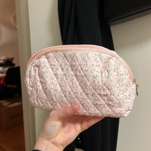 Rosa quiltad necessär med blommönster - Söt rosa necessär med quiltat mönster och små blommor. Perfekt för att förvara smink eller andra småsaker. Den har en dragkedja i matchande rosa färg. Handgjord. Oanvänd 