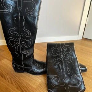 Svarta cowboy boots med vit brodering - Säljer ett par snygga svarta cowboy boots i skinn med cool vit brodering. De har en spetsig tå och är perfekta för både vardag och fest. Bootsens höga skaft ger en riktigt stilren look. Passar perfekt för höst och vinter! Dom är använda 1 gång. Nypris: 925