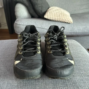 Nike Air Max Terrscape Plus - Säljer ett par svarta nike air max terrascape plus med gröna detaljer i bra skick. De har en cool design med snörning och en slitstark sula. Perfekta för både vardag och träning! 
