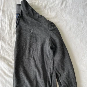 Grå tröja från Polo Ralph Lauren - Säljer en stilren och bekväm grå Polo Ralph Lauren half-zip tröja. Den är långärmad och har en diskret logga på bröstet. Perfekt för både vardag och lite finare tillfällen. (Passar också medium) Frågor? Skriv! 