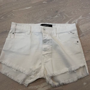 Vita jeansshorts från Replay - Säljer ett par snygga vita jeansshorts från Replay. De har en fräsch fransig kant och knappar framtill. Perfekta för sommaren och passar till nästan allt! 