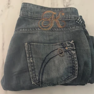 Jeans från Killah med broderad detalj - Säljer ett par snygga jeans från Killah i en cool tvättad blå färg. De har en broderad 'K' detalj på bakfickan och små stjärnor vid fickorna. 