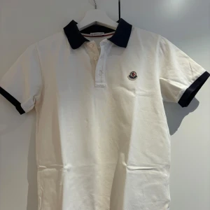 Moncler piké  - Tja! Vi säljer nu denna fina pikén från Moncler. Pikén är använd men har inga defekter. Storleken är 14 och passar dig bäst som är mellan 160-168. Äktehetsbevis finns (se bild 4) och skickas med. Skriv om ni har några frågor eller funderingar!