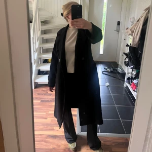 Svart kappa - Säljer denna längre svarta kappa från Vero Moda i storlek XS. Kappan är gjord av ett relativt tjockt material vilket gör att den passar perfekt till hösten men även på varmare vinterdagar.