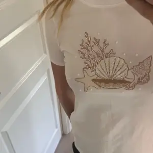 Säljer en superfin vit t-shirt med ett glittrigt snäckmotiv på framsidan. Använd 2 gånger, inga defekter