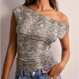 Ormmönstrad oneshoulder topp - Snygg och trendig oneshoulder topp med ormmönster. Nyskick. Toppen är i ett stretchigt material som formar sig efter kroppen. Den är från Nelly. Har bara använt den en gång. 💞💞