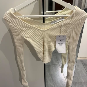 Beige ribbad topp från Bershka  - Säljer en  beige ribbad topp från Bershka. Toppen har en offshoulder-design och långa ärmar. Aldrig använd 