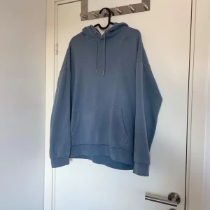 Blå hoodie - Säljer en bekväm blå hoodie med känguruficka och justerbar huva. Perfekt för en avslappnad stil. Den har långa ärmar och en klassisk passform.
