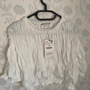 Vit blus från Zara - Säljer en vit blus från Zara. Blusen är croppad och har trekvartsärmar. Endast testad med prislapp kvar.