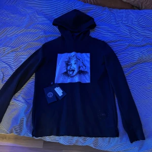 Svart hoodie med tryck - Säljer en svart hoodie från Limitato med ett coolt tryck på framsidan. Tröjan har långa ärmar och en klassisk huva. Perfekt för en avslappnad stil. Ny med taggar kvar.