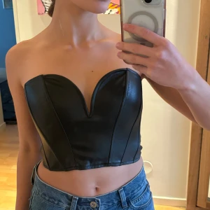 Svart korsett från Zara - Supersexig svart korsett i skinnimitation från Zara. Den har hjärtformad urringning och är axelbandslös. Använd endast ett par gånger så den är i superbra skick🖤