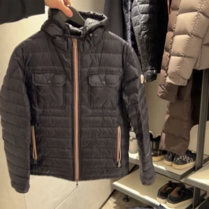 MONCLER JACKA  - Snygg svart quiltad jacka från Moncler med huva och dragkedja. Jackan har två bröstfickor med knappar och två sidofickor med dragkedja. Perfekt för kyligare dagar med sin stilrena design och praktiska detaljer. Skriv för fler bilder!
