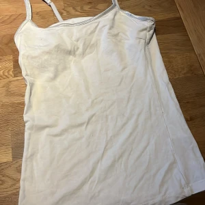 Vit linnetopp från Stockh LM - Säljer en stilren vit linnetopp från Stockh LM i storlek XS. Toppen har smala axelband och en dekorativ ringdetalj på baksidan. Perfekt för varma dagar eller som ett lager under andra plagg. Plagget har lite noppror på banden.