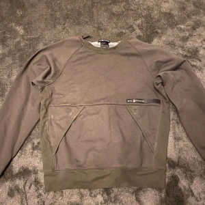 Mörkgrön tröja från Sail Racing - Säljer en mörkgrön tröja från Sail Racing med en praktisk ficka framtill. Använd en gång så typ helt ny. Perfekt för en avslappnad stil. Passar både herr och dam.