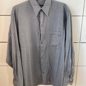 Grå skjorta från Oscar of Sweden - Säljer en stilren grå skjorta från Oscar of Sweden. Skjortan har en klassisk krage och långa ärmar med knappar. Perfekt för både vardag och festliga tillfällen. Materialet känns mjukt och bekvämt, vilket gör den idealisk för alla säsonger!😊