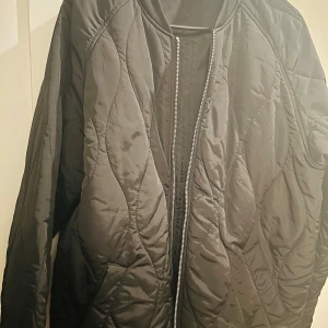 Svart quiltad jacka från xInt - Säljer en svart quiltad jacka från xInt i storlek L. Den har en dragkedja framtill och är långärmad. Perfekt för höst och vår med sin stilrena design och bekväma passform. Jackan är i nyskick och redo för nya äventyr!