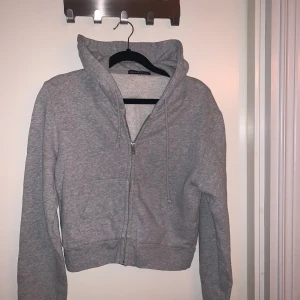 Grå hoodie från Brandy Melville - Säljer en supermysig croppad Hoodie från Brandy Melville. Hoodien är i bra skick och passar till det mesta. Står inte storlek men sitter som en Xs-S