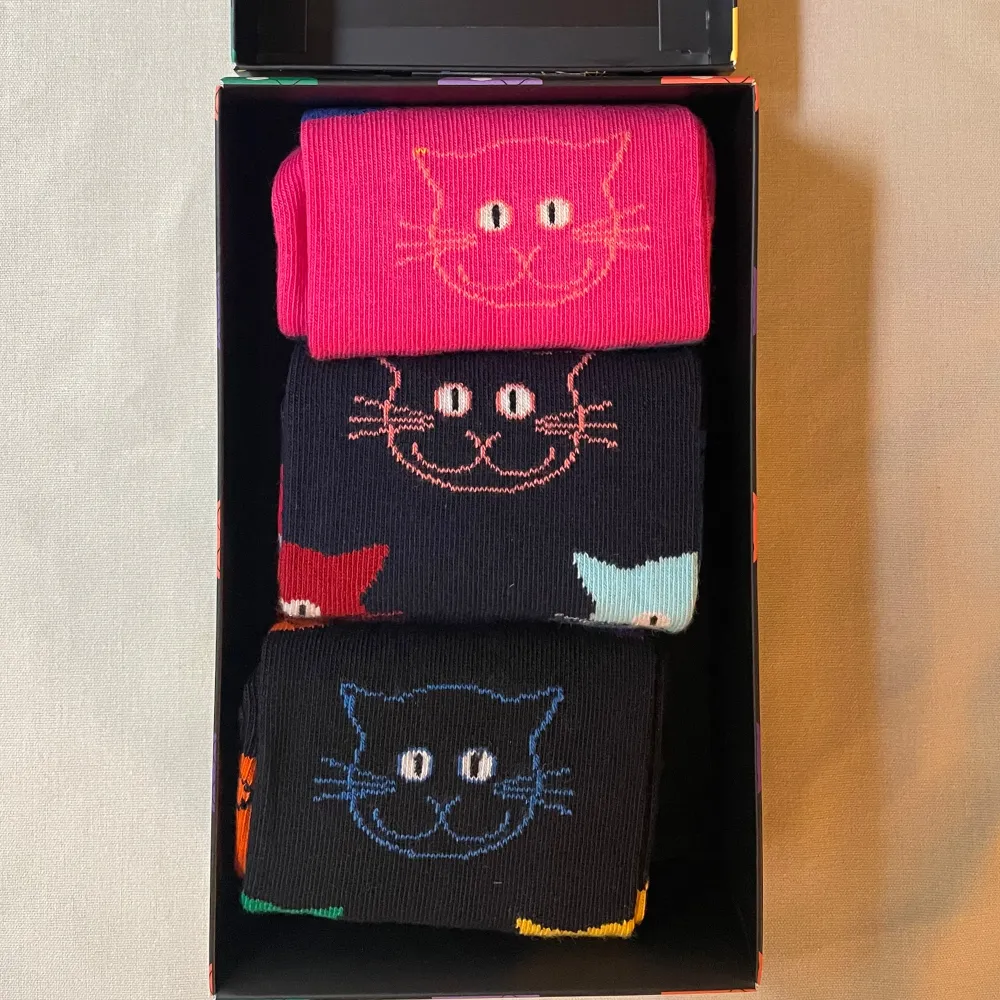 Säljer tre par unisex katt strumpor från Happy Socks.  Strumporna är i nyskick och har en skön passform.. Accessoarer.