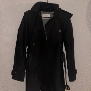 Kappa/Trenchcoat  Zara Women - En superfin och kostym vibbar kappa från Zara Women i storlek S. Fickor, skärp och en stor luva. Fina knappar och väldigt detaljerad jacka. Vattentätt material och väldigt varm. I väldigt bra skick, inga skador/fläckar eller hål.